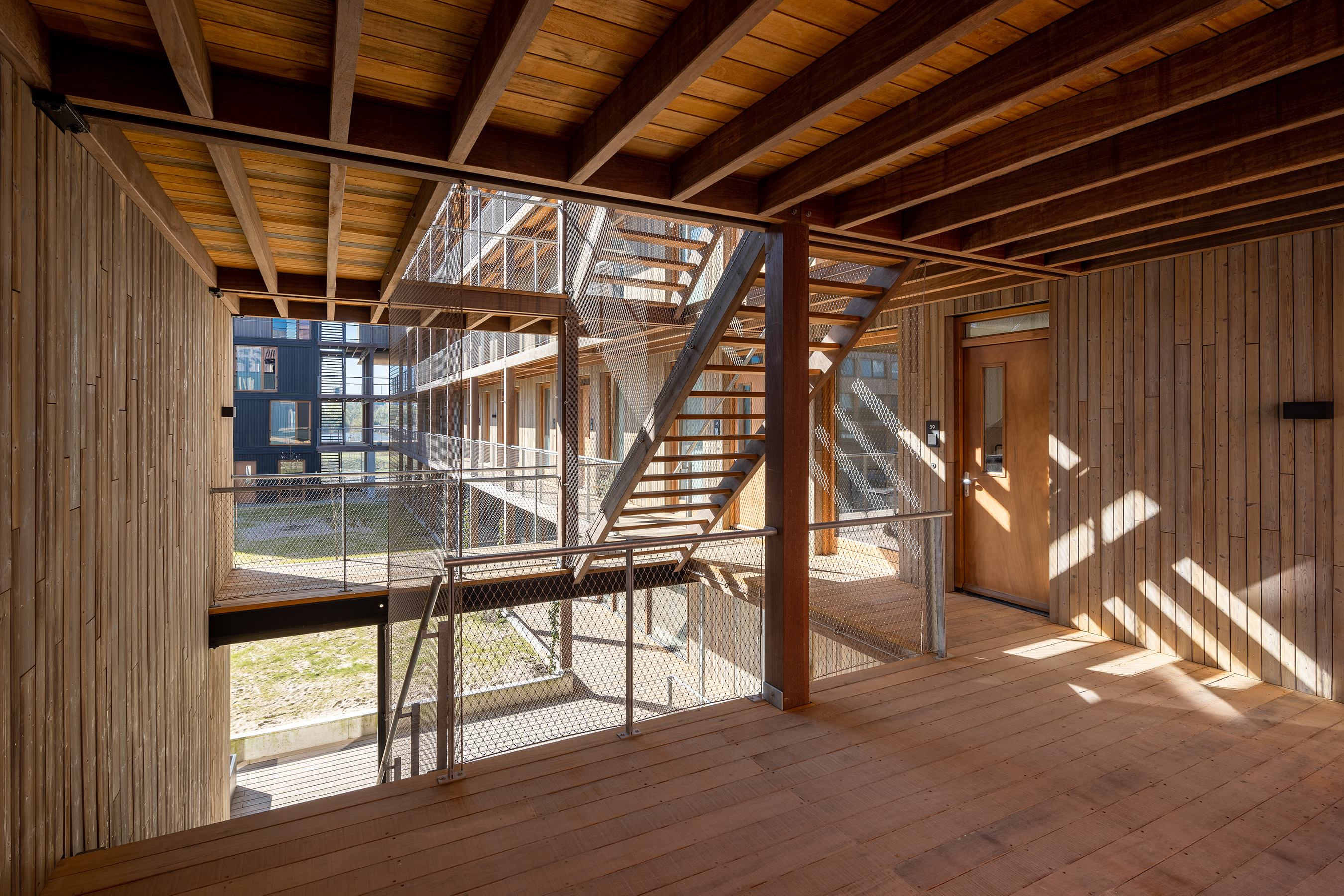 Interior view of Juf Nienke with timber structure and stairs reflecting sustainable housing and eco-friendly building design.