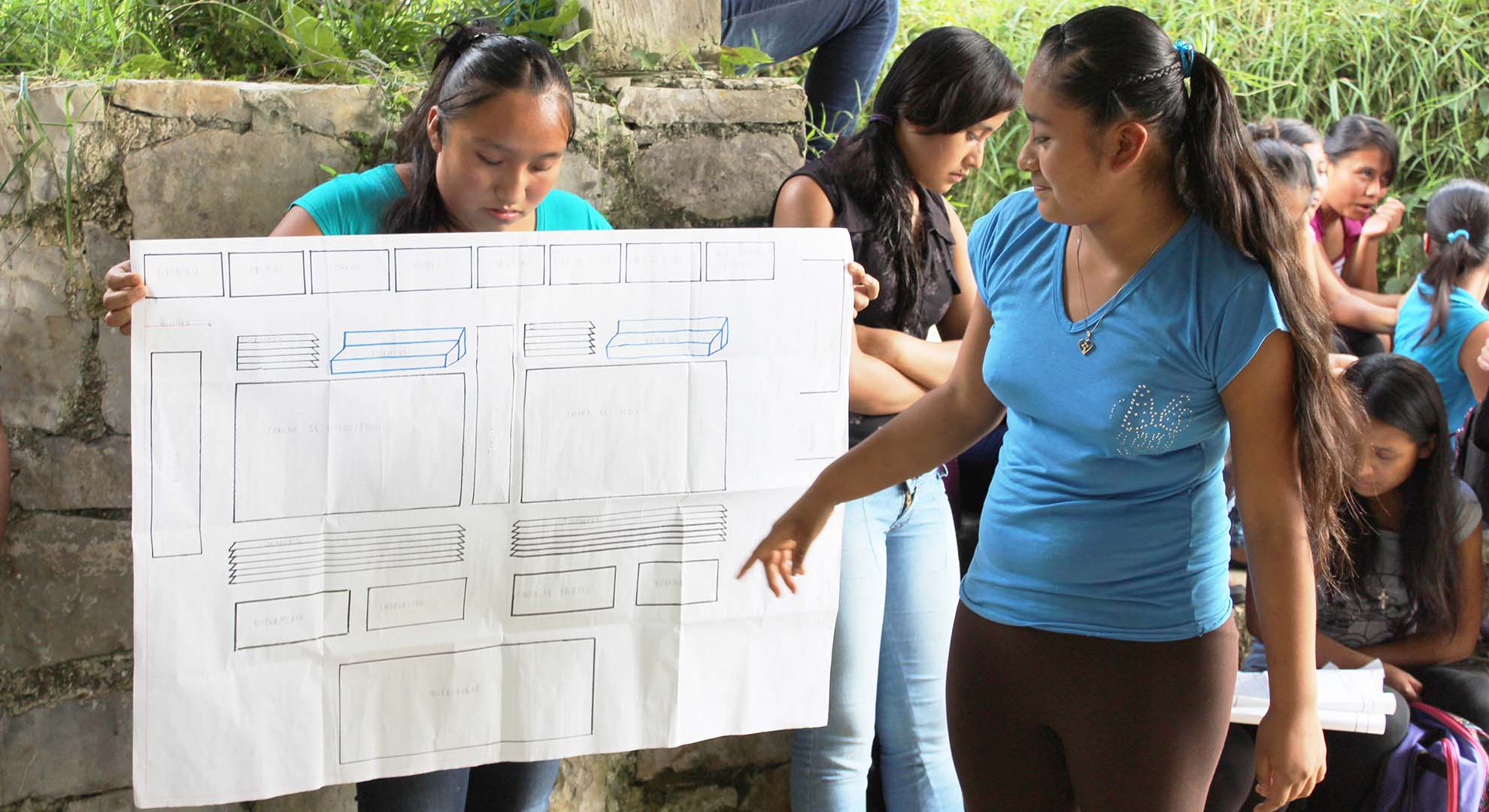 mujeres presentando diseño colaborativo de escuela rural productiva