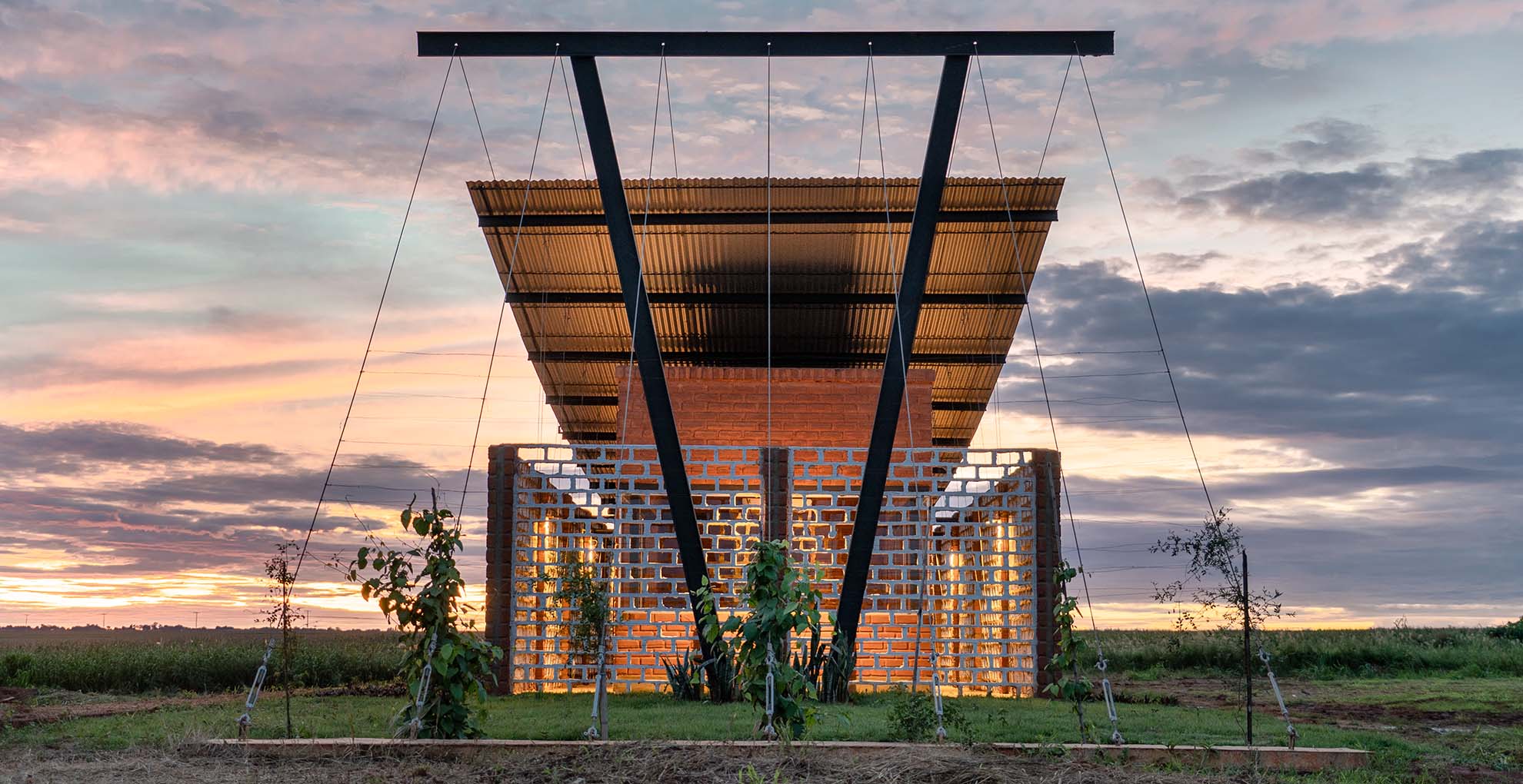 Frontal view of Oficina Nordeste Curuguaty, designed with reuse of local materials to integrate into the landscape.