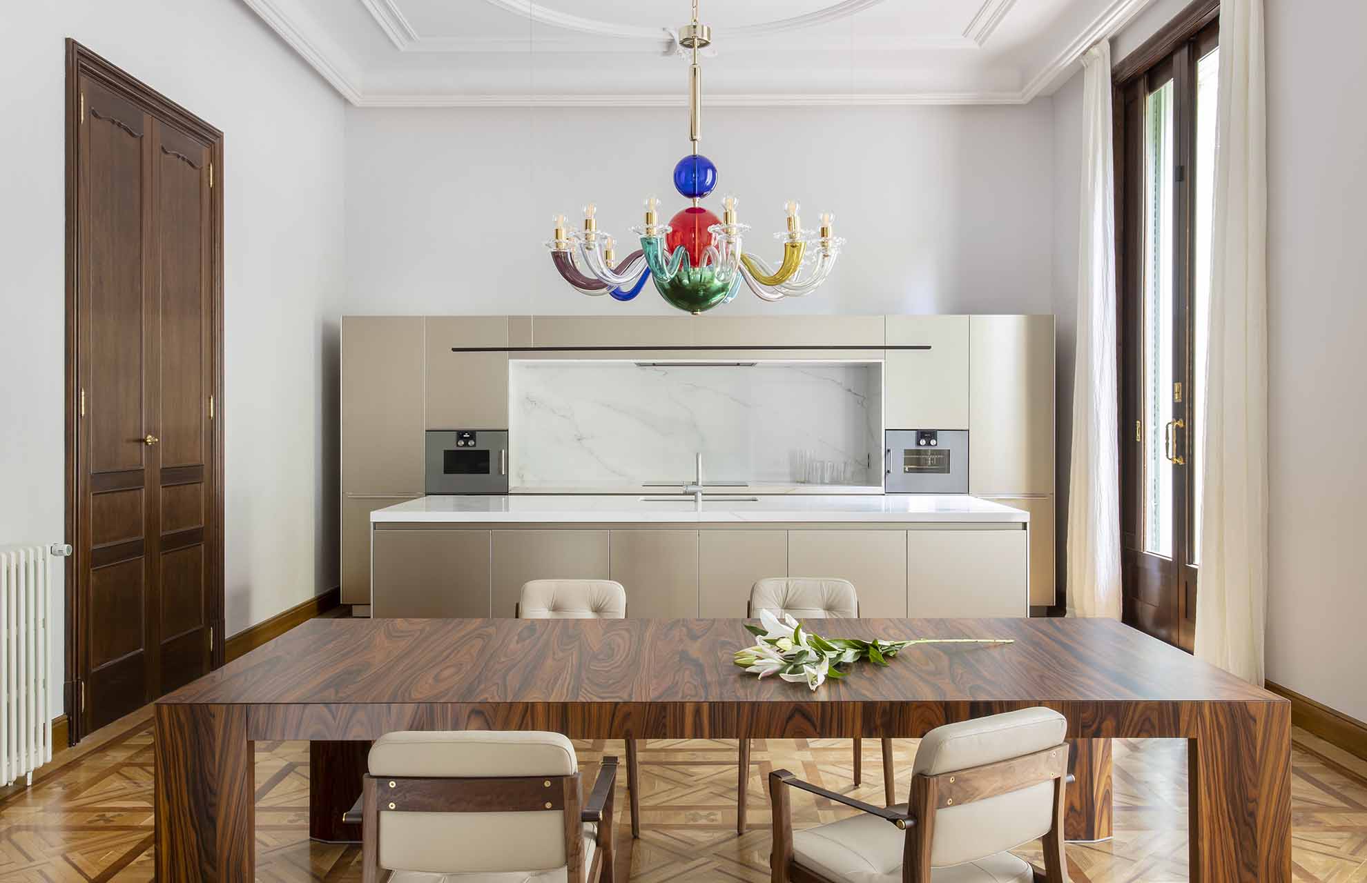 Contemporary kitchen and dining space in a renovated interior, combining modern design with classic building materials like wood and marble.