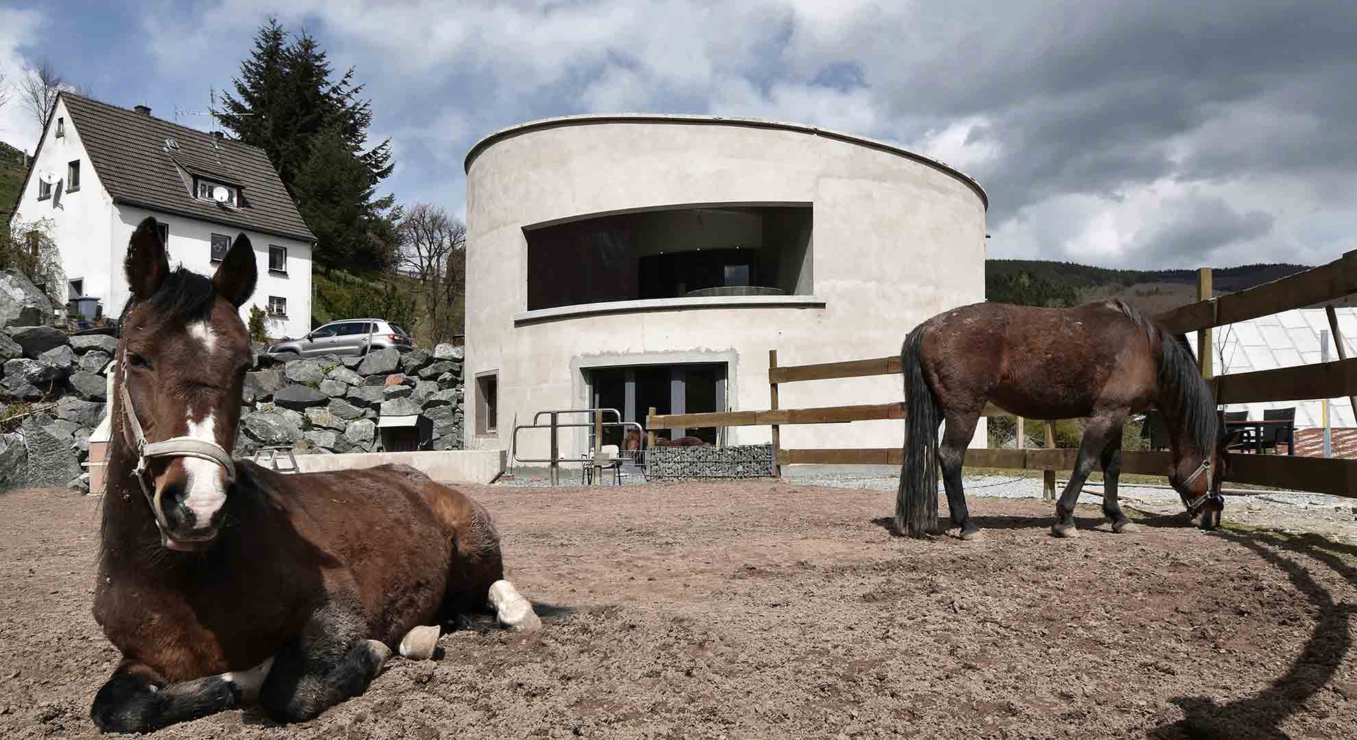 Circular eco-house in a rural setting, designed for energy efficiency and conserving resources while blending with nature.