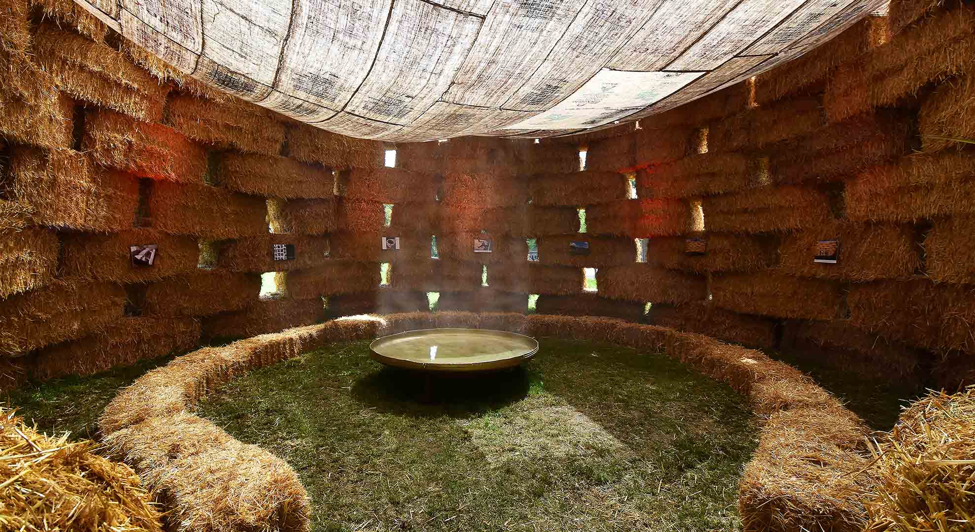 Interior of a circular space built with straw bales, showcasing sustainable design principles focused on conserving resources.