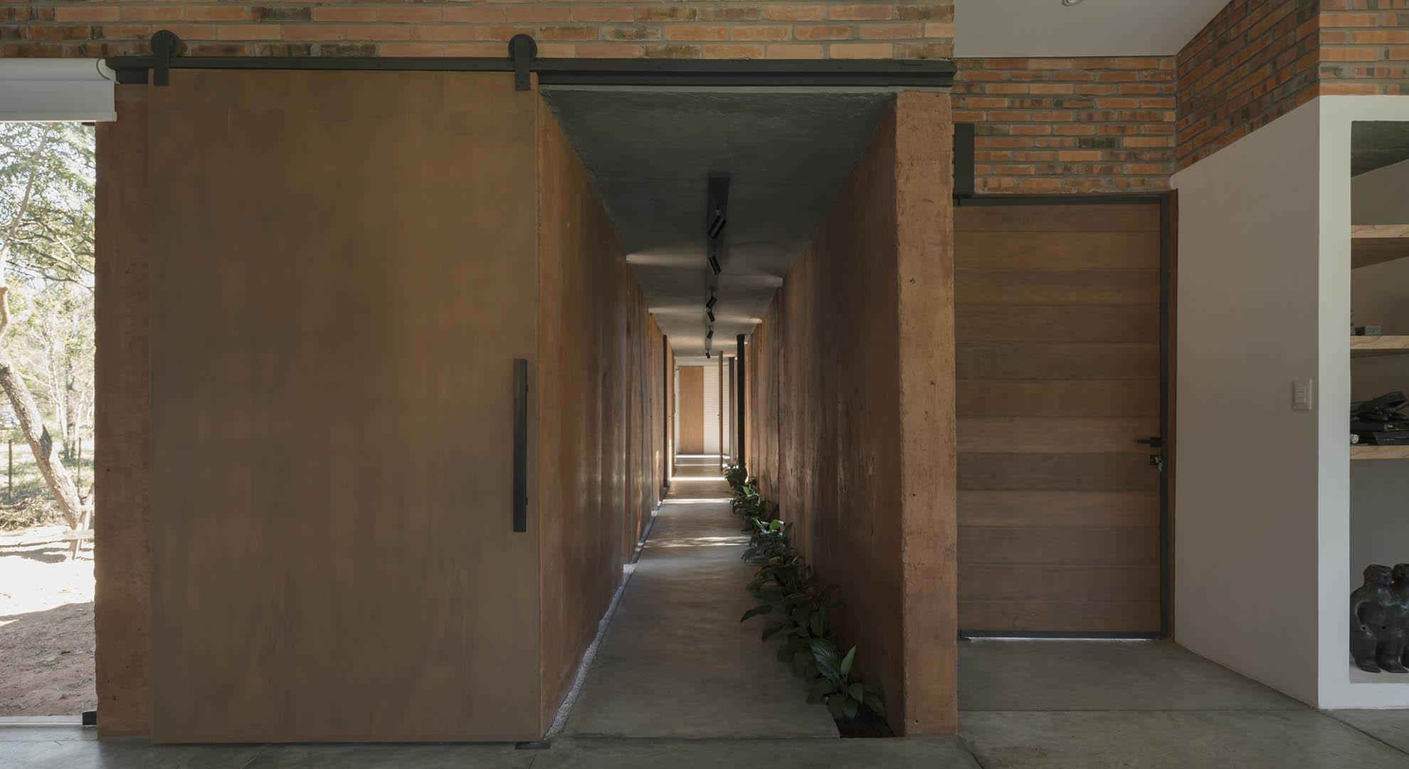 Interior corridor of Luce and Pablo House, featuring walls built by reusing soil and sustainable materials.